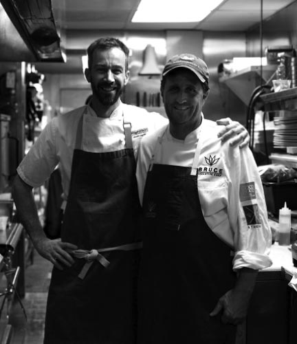 two male chefs posing and smiling in restaurant kitchen
